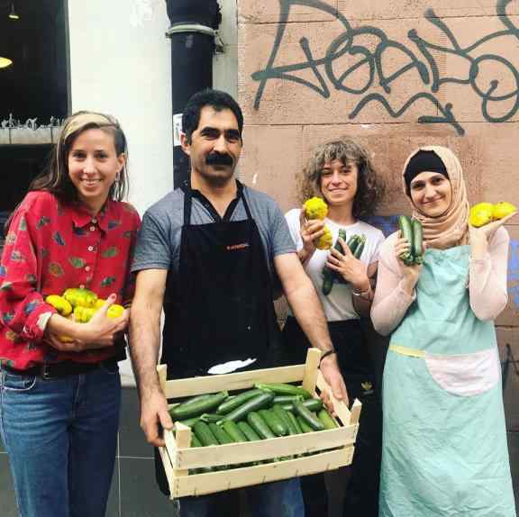 4 osoby - 3 kobiety i meżczyzna - pozują, uśmiechając się. W rękach trzymają różna warzywa - cukinie i dynie.
