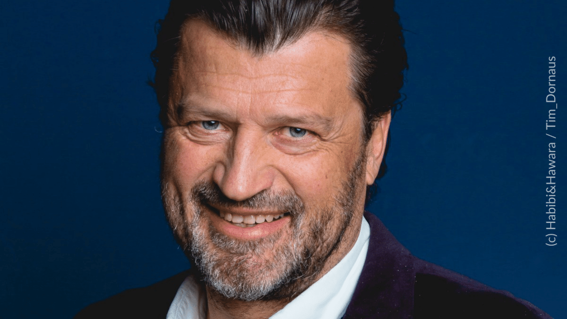 Photo of white man with beard and in a suit smiling at the camera 