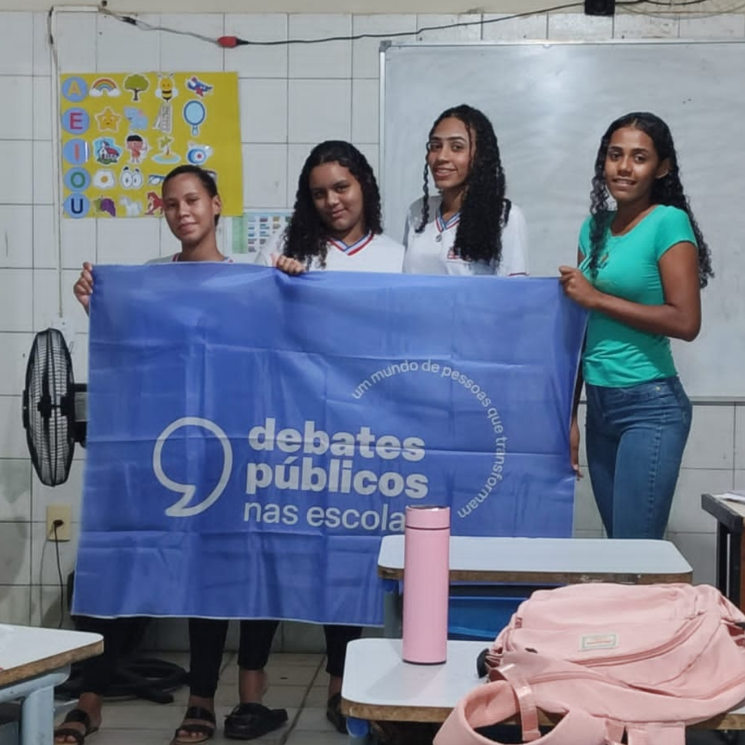 Um grupo de jovens 4 jovens segurando a bandeira dos Debates Públicos das Escolas