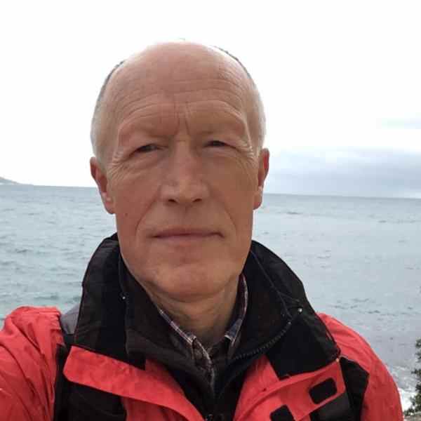Zdjęcie przedstawia selfie Wacława Idziaka w czerwono-czarnej kurtce zimowej na tle morza. Wacław delikatnie się uśmiecha.