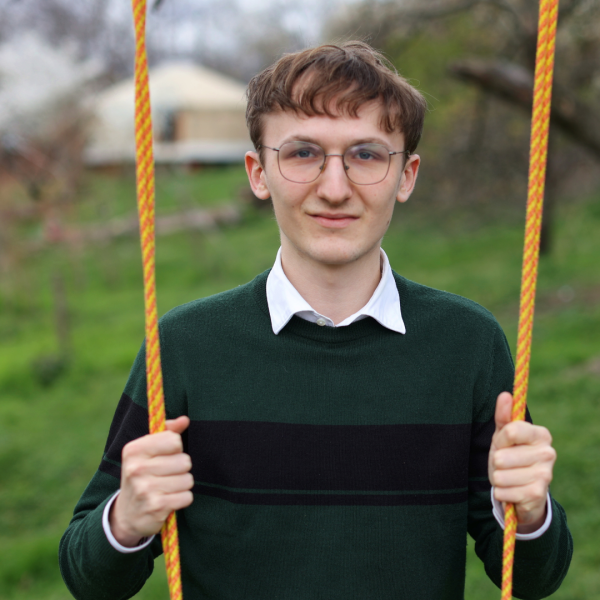 Young man with glasses standing outside holding swing strings