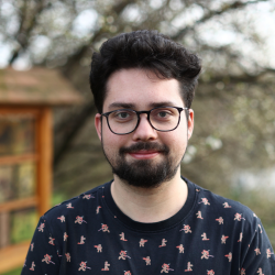 Young man with a beard and glasses standing outside