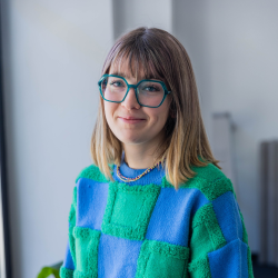 Young woman wearing glasses and a jumper, smiling