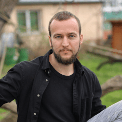 Youn man with a beard sitting outside wearing black shirt