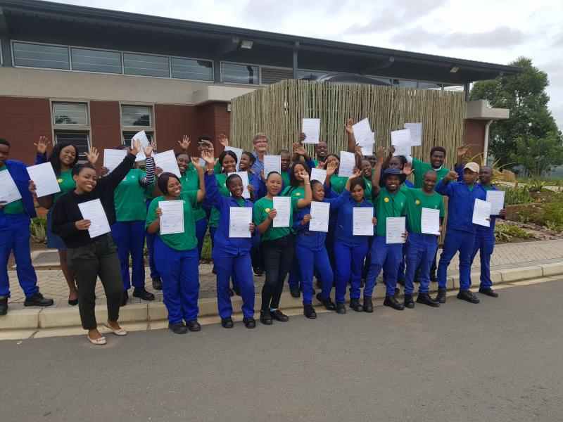 Group of smiling colleagues from South Africa holding up paper certificates