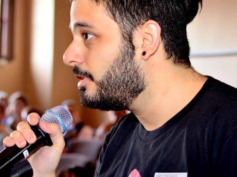 Lebanese man with a beard and a small pony tail holding a mic
